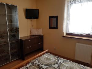 a bedroom with a television and a dresser and a window at Wigwam Apartament 6-osobowy in Sopot