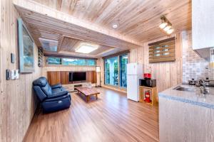 a kitchen and living room with a chair and a refrigerator at Dongbackdongsan Pension in Jeju