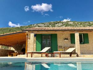 a house with two lounge chairs next to a swimming pool at Villa Dule in Pakoštane