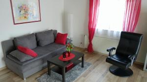 a living room with a gray couch and a black chair at Ferienwohnung Allgäuleben 68m2 in Amberg