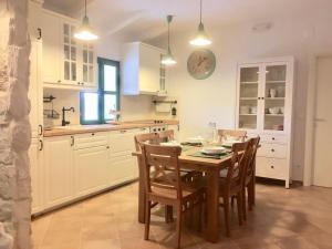 a kitchen with a table with chairs and a clock on the wall at Villa Dule in Pakoštane