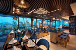 a restaurant with tables and chairs and a person in the background at Grand Dragon Hotel Hanoi in Hanoi