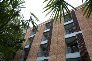 a tall brick building with windows and palm trees at The Coconut Hotel in Lampang