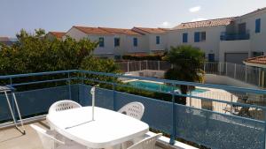 een balkon met een tafel en stoelen en een zwembad bij Appartement tout confort dans résidence avec piscine in Vaux-sur-Mer