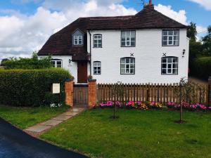 a white house with a fence and flowers at The Rag House in Upton upon Severn