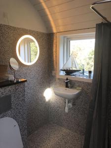 ein Badezimmer mit einem Waschbecken und ein Fenster mit einem Boot. in der Unterkunft Holldiay house near the beach in Yderby