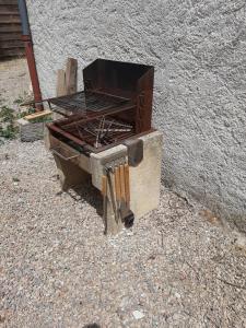un barbecue posé sur le sol à côté d'un mur dans l'établissement MARTIN's COTTAGE Tourrettes, à Tourrettes