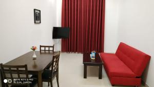 a living room with a red couch and a table at Azaiba Hotel Apartments in Muscat