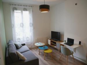 een woonkamer met een bank en een bureau met een laptop bij Appartement écologique - Proche Métro Charpennes in Villeurbanne