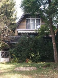 a house with a balcony and a tree at Franz Berg Apartman in Tököl