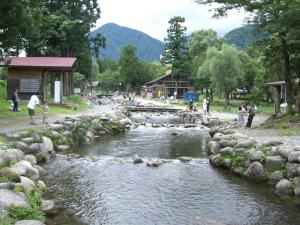 湯澤的住宿－湯澤銀水木屋酒店，一群人站在河里,围着岩石