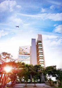 un avion survolant un grand bâtiment avec des arbres dans l'établissement Bluewater Hotel Xpark Gloria Outlets Taoyuan Baseball Stadium, à Dayuan