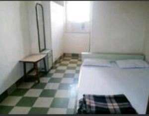 a room with a bed and a table and a checkered floor at Continental Guest House in Kolkata