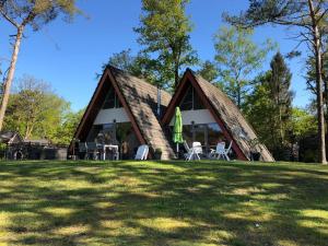 una cabaña en el bosque con sillas en la hierba en 't Vosseven vakantiepark, en Stramproy