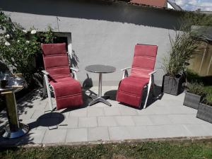 HinterweilerにあるFerienwohnung Adamsのパティオ(赤い椅子3脚、テーブル付)