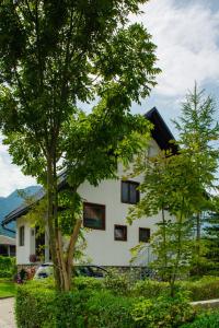 ein weißes Haus mit einem Baum davor in der Unterkunft Apartment Ana in Bohinj