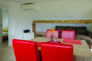 a dining room table with red chairs and a couch at Apartment Ana in Bohinj