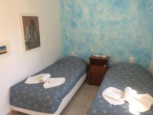 a bedroom with two beds and a dresser with towels at Angies House in Skopelos Town