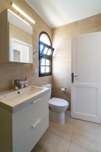 uma casa de banho com um WC, um lavatório e um espelho. em Casa Hugo em Costa Calma
