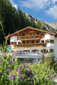 ein großes Gebäude mit einem Balkon mit Blumen davor in der Unterkunft Hotel Astoria in Samnaun