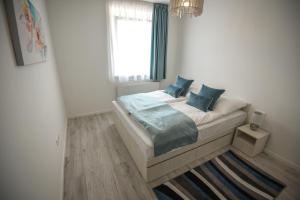 a bedroom with a bed with blue pillows and a window at Francesca Apartman in Siófok