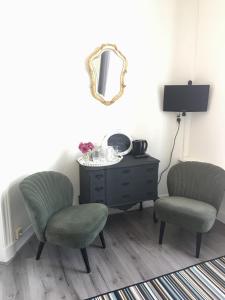 Zimmer mit 2 Stühlen, einer Kommode und einem Spiegel in der Unterkunft B&B Zeeuws genoegen in Vlissingen