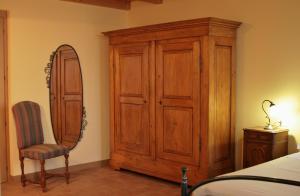 una camera da letto con armadio in legno, sedia e specchio di Agriturismo Cavrigo a Lodi