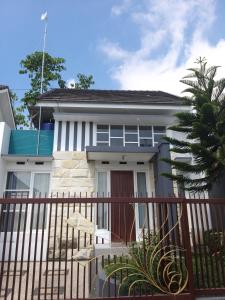 a white house with a red door and a fence at Ken's Villa 8 in Batu
