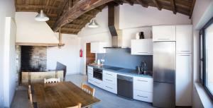 a kitchen with white cabinets and a wooden table at A casa do viveiro in Dormeá