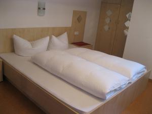 een bed met witte lakens en kussens erop bij Appartement Geisler in Zell am Ziller