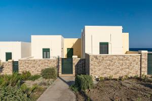 una fila de casas blancas con puertas verdes en House Myrtos en Lakhaniá