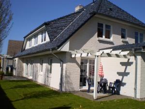 a white house with a table and chairs in front of it at Am Ostseestrand 1 in Zingst