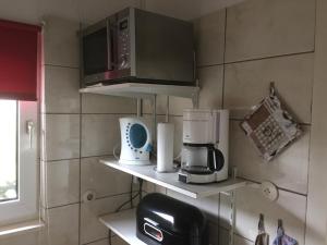 a kitchen with a microwave and appliances on shelves at Europa-Feriendorf Husen in Husen +15 photos