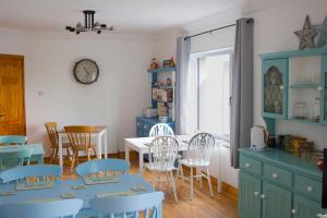 comedor con mesa, sillas y reloj en Madra Rua Organic Accommodation, en Ballyliffin