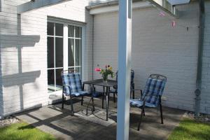 a patio with three chairs and a table with flowers on it at Am Ostseestrand 1 in Zingst