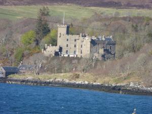 a castle on a hill next to a body of water at Harlosh Hideaways - Stargazer Pod in Harlosh