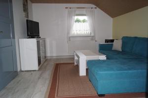 a living room with a blue couch and a tv at Ferienwohnung Familie Arlt in Königstein an der Elbe