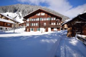 a snow covered building in front of a mountain at Studio bim Chalet bim Chilchli in Mürren