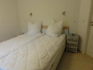 Schlafzimmer mit einem Bett mit weißer Bettwäsche und Kissen in der Unterkunft 3 Zimmer Ferienwohnung Haus Meeresblick Turmwohnung mit Meerblick und Südbalkon A404 in Baabe