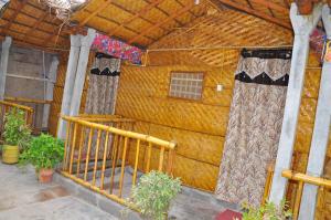a wooden house with curtains and a balcony at Khushi Cottage in Hampi