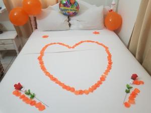 Una cama con un corazón hecho de globos naranjas en St. James Guesthouse, en Roseau