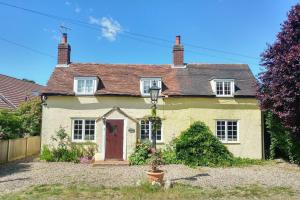 a small yellow house with a red door at The Bird House at Woodburn Cottage in Dedham