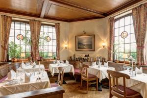a restaurant with tables and chairs and windows at Wellness Privathotel Post an der Therme in Badenweiler