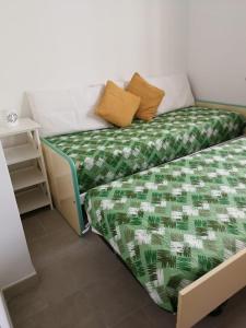 ein Bett mit einer grünen und weißen Bettdecke darauf in der Unterkunft la caravella in Santa Croce Camerina