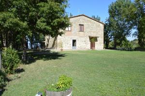 an old stone house in a field with a yard at Casale in toscana in Sarteano