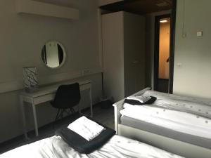 コラリにあるHotelli Kolariのベッド2台、デスク、鏡が備わる客室です。