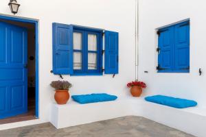 a white wall with blue windows and blue pillows at House Salvia in Lachania