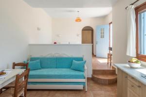 a living room and kitchen with a blue couch at Asterias House in Donoussa