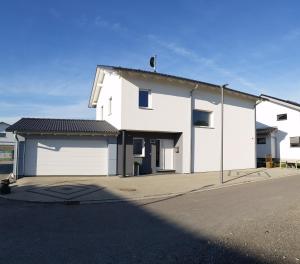 una casa blanca con un garaje en una calle en Ferienwohnung Pfaffenberg, en Oberteuringen