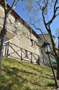 a stone building with a gate and a tree at La Petronilla Appartamenti Montepetriolo in Monte Petriolo